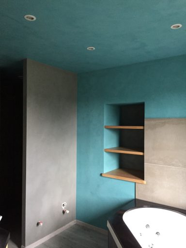 Mur intérieur bleu turquoise avec étagères en bois, coin d'une salle de bain moderne.